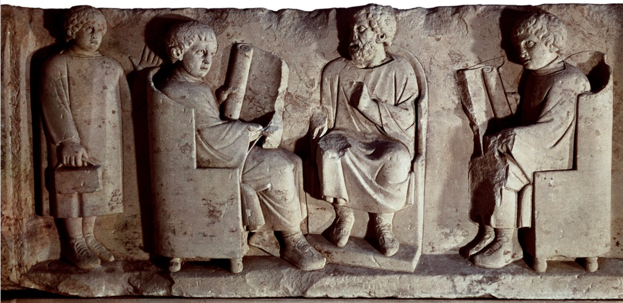 Ancient Roman stone relief showing a seated teacher and pupils